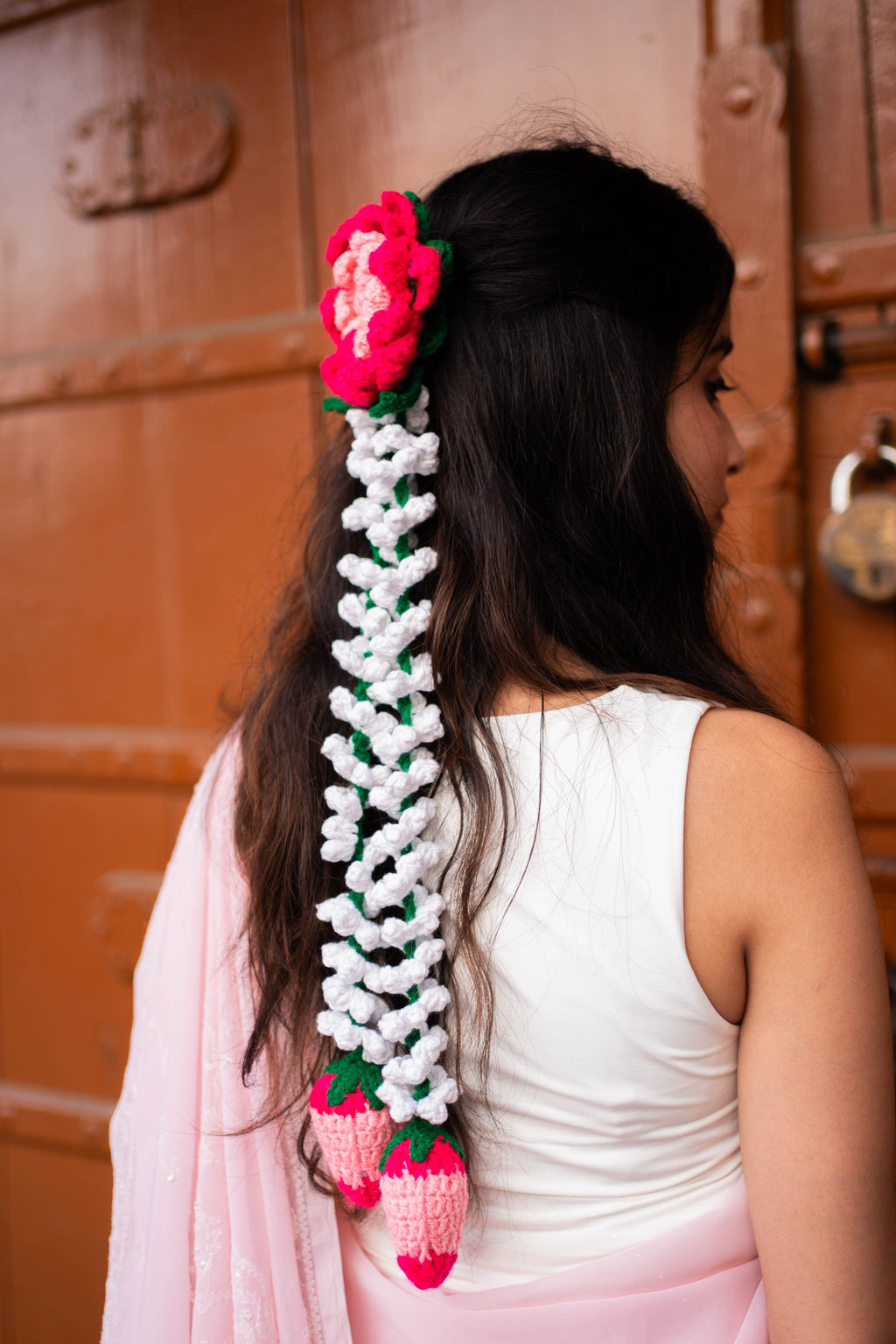 Woman with a braided hair accessory featuring flowers and leaves against a wooden door background that always bloom.